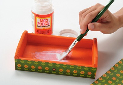 Painting Mod Podge Gloss inside of a painted wood tray with a green handled paint brush