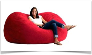 Девушка сидит в большой красной напольной подушке